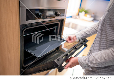 Male hand opening oven door Male hand opening oven door 71587832