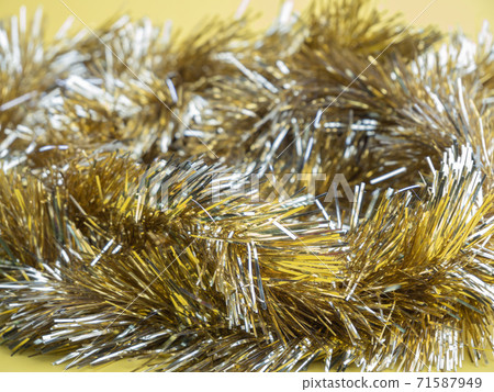 Golden and silver  tinsel, Christmas ornament on yellow background background.. 71587949