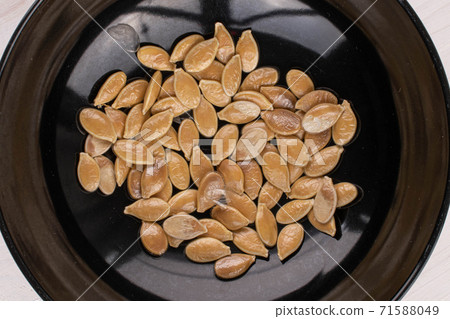 Pumpkin seed on white wood 71588049