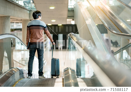 Male tourist carrying suitcase luggage on travelator 71588117