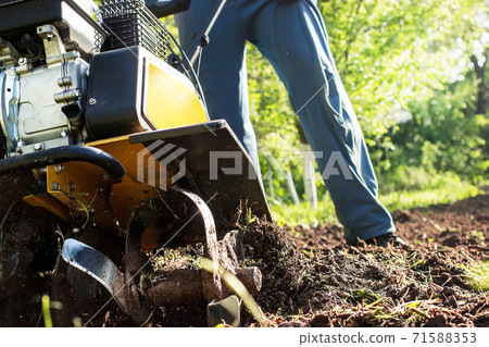 A man plowing a soil by motor cultivator A man plowing a soil by motor cultivator 71588353