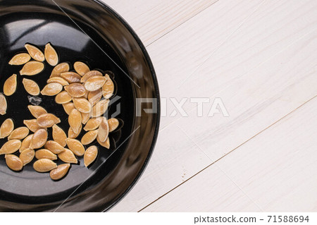 Pumpkin seed on white wood Pumpkin seed on white wood 71588694