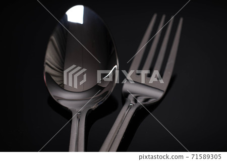 Steel cutlery on black glass 71589305