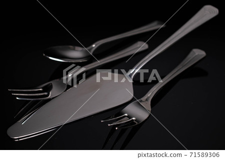 Steel cutlery on black glass 71589306