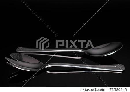 Steel cutlery on black glass 71589343