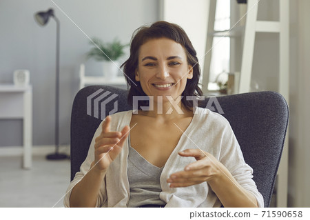 Smiling woman explaining something with hands during online meeting from home 71590658