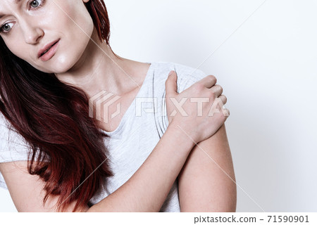 A woman holding on to her shoulder that hurts. A woman holding on to her shoulder that hurts. 71590901