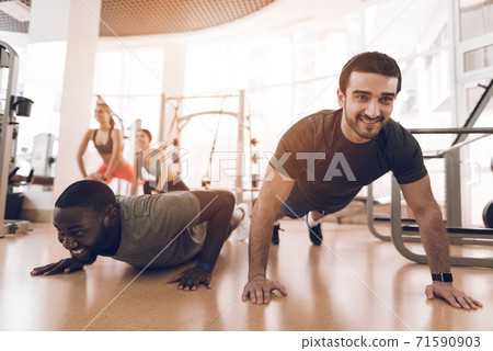 The two men squeeze off the floor in a modern gym. The two men squeeze off the floor in a modern gym. 71590903
