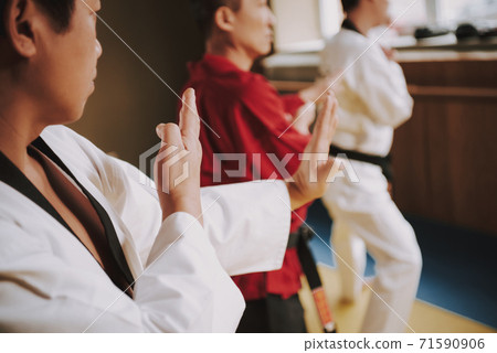 A man in a white kimono holds his hands in drains. 71590906