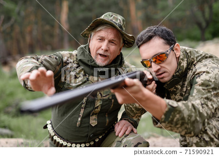 Hunters Shoot in Summer Forest with Shotgun. Hunters Shoot in Summer Forest with Shotgun. 71590921