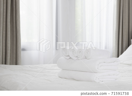 Stack of white towels on white bed in modern bedroom Stack of white towels on white bed in modern bedroom 71591738