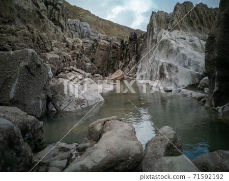A large rock pool sitting between the tides with smooth rocks from sea erosion. Location: Caswell Bay, Gower, Wales, UK 71592192