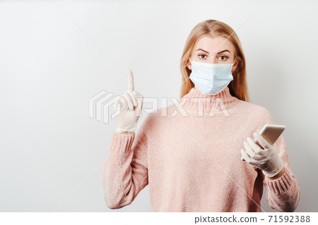 Surprised woman holding smartphone pointing finger 71592388
