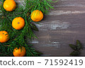 Tangerines with fir and pine branches and cones on a brown wood background. Postcard for Christmas and New Year. Top view 71592419