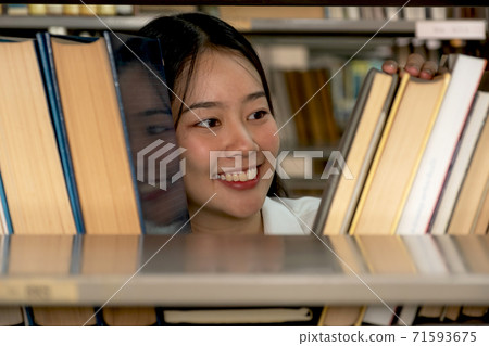Young Asian female college students research and learn from textbooks in the university library Young Asian female college students research and learn from textbooks in the university library 71593675