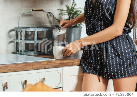 Close up view of female hand pouring coffee from the geyser coffee maker Close up view of female hand pouring coffee from the geyser coffee maker 71593804