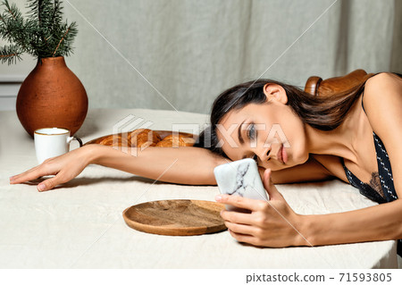 African American woman reading news on smartphone while waiting for coffee to brew on electric stove African American woman reading news on smartphone while waiting for coffee to brew on electric stove 71593805