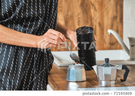 Close up view of hand pouring ground coffee into the geyser coffee maker 71593809