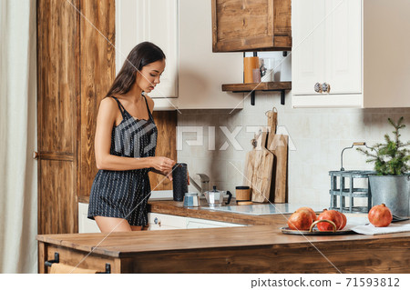 Mixed race woman pouring ground coffee into the coffee maker Mixed race woman pouring ground coffee into the coffee maker 71593812