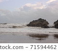 Waves crashing against a large rock as the tide moves in on Caswell Bay Beach, in Gower, Wales, UK. 71594462