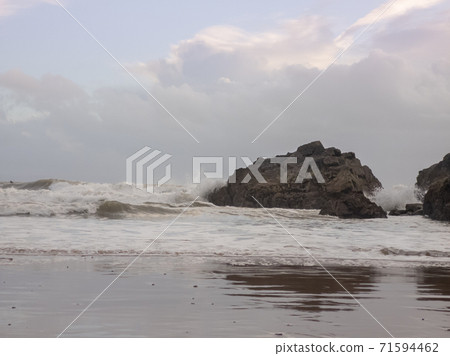 Waves crashing against a large rock as the tide moves in on Caswell Bay Beach, in Gower, Wales, UK. Waves crashing against a large rock as the tide moves in on Caswell Bay Beach, in Gower, Wales, UK. 71594462