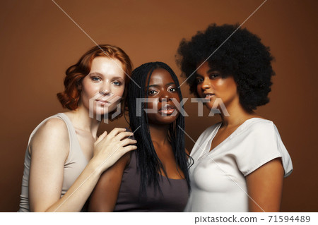 young pretty caucasian, afro, scandinavian woman posing cheerful together on brown background, lifestyle diverse nationality people concept 71594489