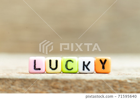 Colorful bead with black letter in word lucky on wood background Colorful bead with black letter in word lucky on wood background 71595640
