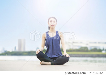 Young woman doing yoga on the beach in the city Young woman doing yoga on the beach in the city 71596164