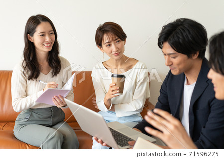 Four young men and women sitting on the sofa in the business office and having a meeting 71596275