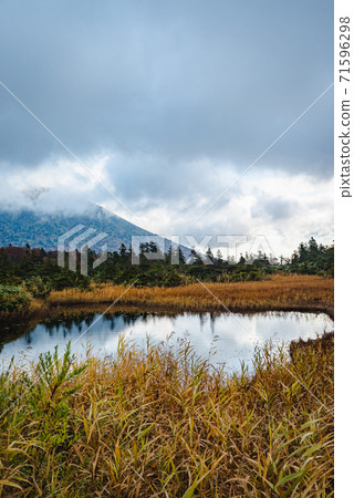 A landscape of a pond with beautiful reflections of cloudy mountains and autumn leaves 71596298