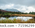A landscape of a pond with beautiful reflections of cloudy mountains and autumn leaves 71596299