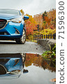 A car reflected in a puddle on the road in the autumn leaves 71596300