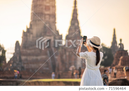 Happy tourist woman in white dress taking Photo by mobile smartphone, during visiting in Wat Chaiwatthanaram temple in Ayutthaya Historical Park, summer, solo, Asia and Thailand travel concept Happy tourist woman in white dress taking Photo by mobile smartphone, during visiting in Wat Chaiwatthanaram temple in Ayutthaya Historical Park, summer, solo, Asia and Thailand travel concept 71596464