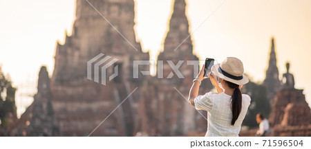 Happy tourist woman wearing surgical face mask and taking Photo by mobile smartphone, protection COVID-19 pandemic during visiting in Ayutthaya temple. new normal, safety travel and travel concept Happy tourist woman wearing surgical face mask and taking Photo by mobile smartphone, protection COVID-19 pandemic during visiting in Ayutthaya temple. new normal, safety travel and travel concept 71596504