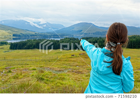 Young woman pointing the mountains - Loch Tulla Viewpoint - Scotland - United Kingdom 71598210