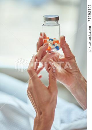 Female hands holding pills in glass bottle 71598501