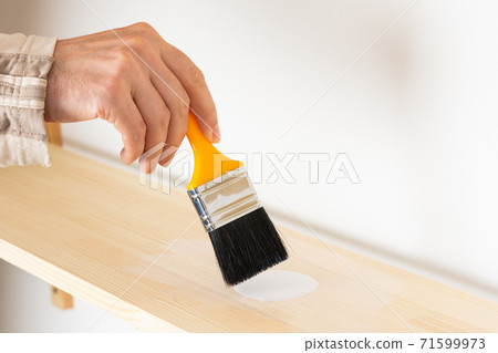 Painter varnishes the bookshelf 71599973