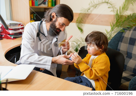 Paediatrician doctor examining a child in comfortabe medical office 71600196