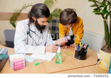 Paediatrician doctor examining a child in comfortabe medical office 71600258