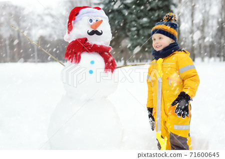 Little boy playing with funny snowman. Active outdoors leisure with children in winter. Little boy playing with funny snowman. Active outdoors leisure with children in winter. 71600645