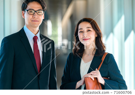 Business image of men and women standing side by side in the office corridor 71600706