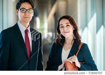 Business image of men and women standing side by side in the office corridor 71600707