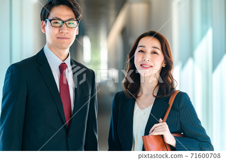 Business image of men and women standing side by side in the office corridor 71600708