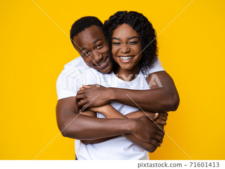 Loving black couple cuddling on yellow background 71601413