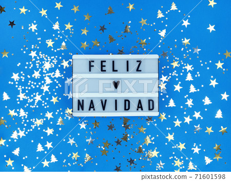 Light box with Feliz Navidad phrase, Spanish Merry Christmas on a blue background with confetti. Light box with Feliz Navidad phrase, Spanish Merry Christmas on a blue background with confetti. 71601598