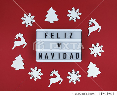 Light box with Feliz Navidad phrase, Spanish Merry Christmas on a red background with wooden toys. 71601601