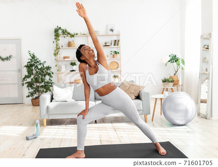 Fit black woman stretching her body on yoga mat during her home workout Fit black woman stretching her body on yoga mat during her home workout 71601705