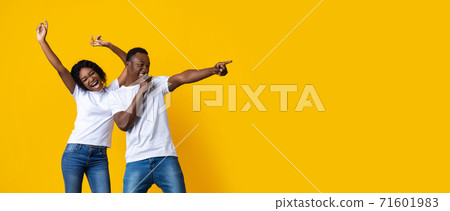 Positive black couple singing and dancing, pointing at empty space Positive black couple singing and dancing, pointing at empty space 71601983
