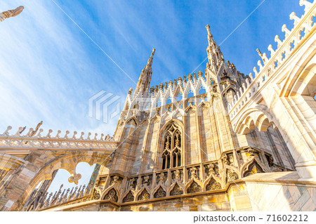 Roof of Milan Cathedral Duomo di Milano with Gothic spires and white marble statues. Top tourist attraction on piazza in Milan, Lombardia, Italy. Wide angle view of old Gothic architecture and art. 71602212