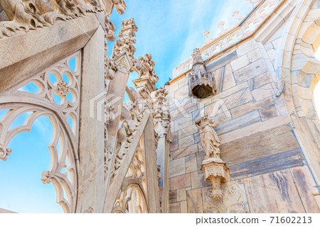 Roof of Milan Cathedral Duomo di Milano with Gothic spires and white marble statues. Top tourist attraction on piazza in Milan, Lombardia, Italy. Wide angle view of old Gothic architecture and art. 71602213